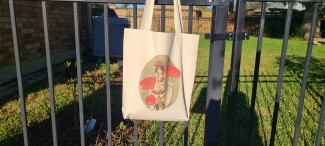 Natural cotton tote bag featuring a girl wearing a red straw hat, surrounded by red topped fly agaric mushrooms.